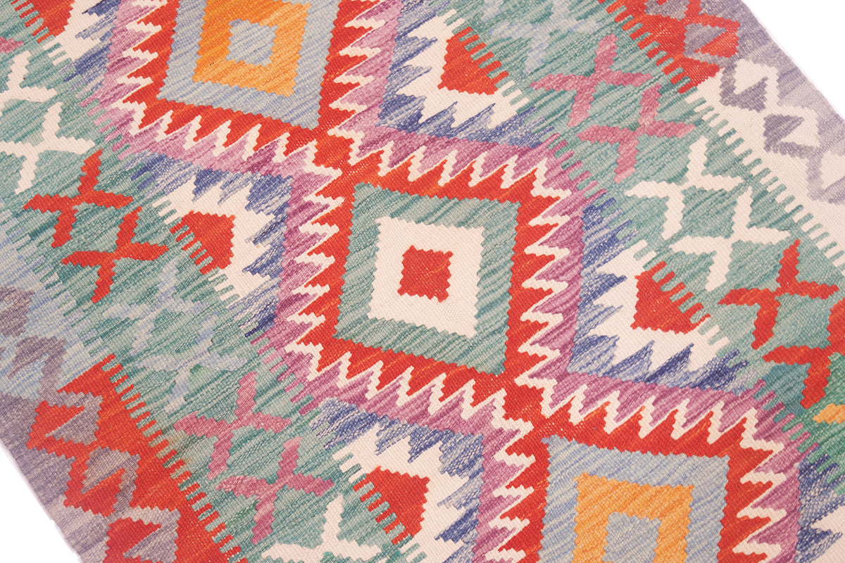 Close-up of colorful kilim rug texture with orange, teal, and red geometric shapes