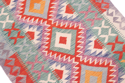 Close-up of colorful kilim rug texture with orange, teal, and red geometric shapes