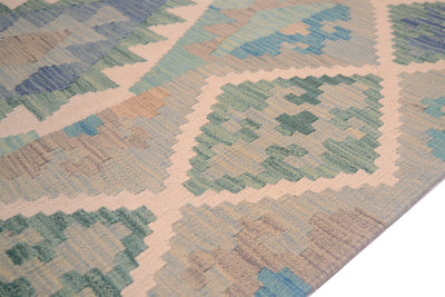 A close-up of a handwoven Kilim rug from Afghanistan with a geometric diamond pattern in muted shades of blue, green, beige, and cream.