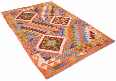 A Handwoven Afghan Kilim wool rug with a vibrant geometric pattern in orange, beige, brown, green, and blue, shown from an angled perspective against a plain white background.
