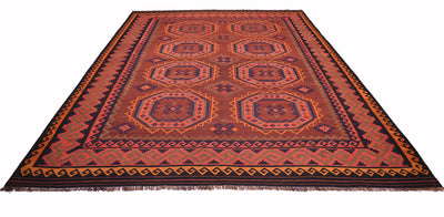 A rectangular woven old Afghan Kilim with a geometric tribal pattern in rust red, orange, brown, and black, featuring a fringed edge on a white background.