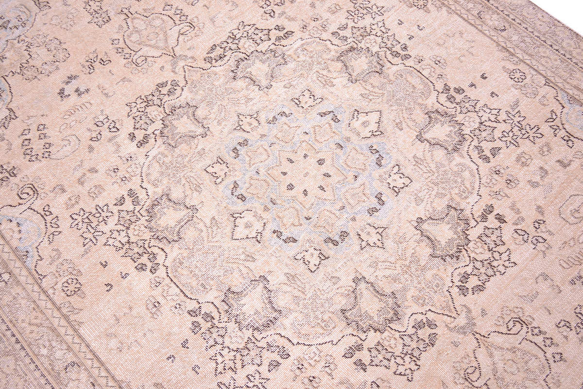 Close up detail of vintage handmade carpet in soft colours of cremy beige and white cotton warps with light powder blue andsoft beige and ligth brown detailing. Handknotted shaved pile and floral pendatned traditional lobed floral medallion.