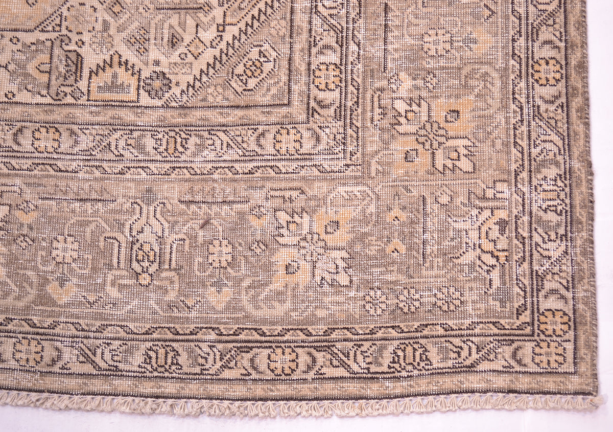 Corner detail of vintage carpet with gold beige, light brown and dark brown colour wih floral geometrac motif woven on a cotton foundations with cotton warp fringes,