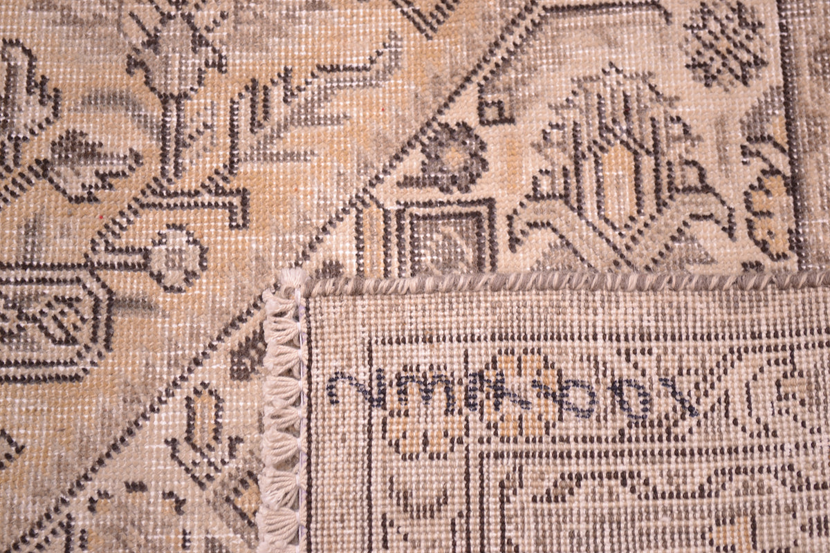 Reverse of carpet showing knotting of distressed shaved pile in cream, beige, brown and light gold neutrals in colourway. Light cream beige main ground. 