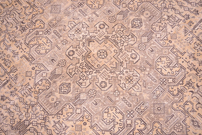 Detailed close up view of main medallion fo floral geometric carpet with beige, gold, brown and hints of sage green. Handknotted vintage carpet with zero pile but sturdy cotton foundation warps.
