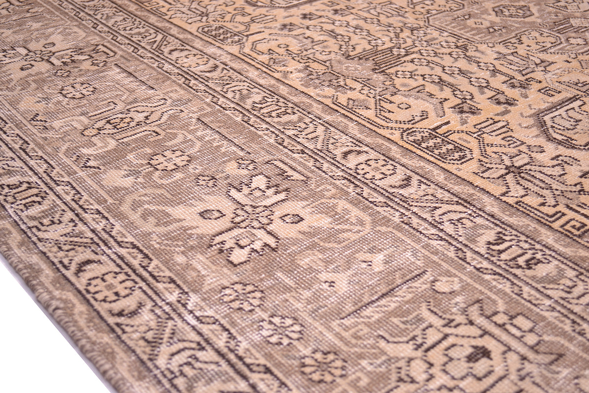 Detail of border of vintage carpet with light brown background colour and floral geometric patterning. Dark brown detailing and outling of geometric motifs and stylized flowers and leaves.