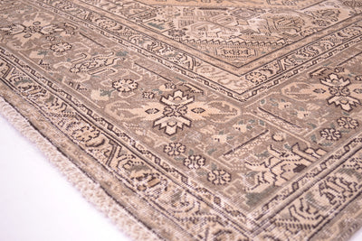 Corern detailng showing shaved zero distressed pile fo vintage carpet in beige, gold and brown. Hints of sage green in detailing but subtle hue. Floral geometirc traditonal format with softened colours. Notice signature of weaver in innerborder.