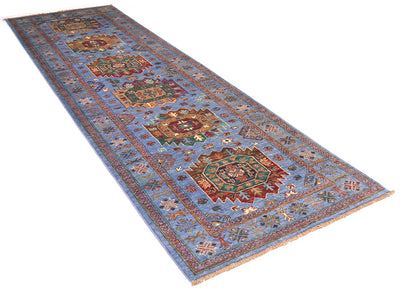 A long rectangular handmade Waziri Afghan runner with a light blue field and ornate multicoloured medallion motifs, shown on a plain white background.