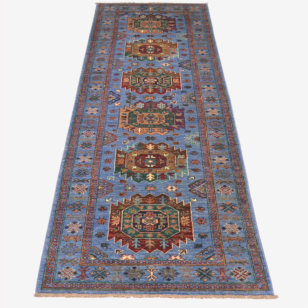 A 9'6 long rectangular handmade Waziri runner with a traditional geometric pattern, featuring a light blue field, red borders, and four large central medallions, shown flat against a white background.