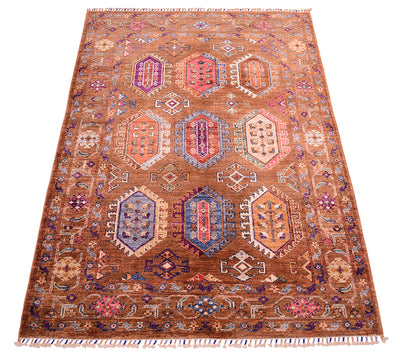 A 6x4 rectangular Afghan cinnamon Waziri rug area rug with a warm brown base and a complex geometric medallion pattern in red, blue, purple, beige, and orange, finished with fringed edges.