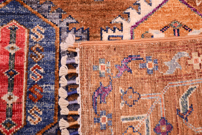 Close-up of the corner turned up revealing the hand-knotted weave of a handmade Afghan brown Waziri rug. 