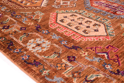 A close-up of a traditional patterned handmade Afghan brown Waziri rug with a warm rust-brown base and geometric medallion motifs in beige, red, blue, and purple.