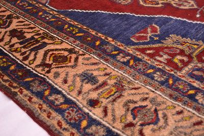 Close-up of an ornate patterned old Yahyali rug showing a beige central field bordered by navy blue and red sections with intricate geometric and floral motifs.