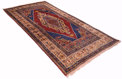 A traditional Old Turkish Yahyali area rug with a central red medallion, surrounded by navy blue and beige patterns, shown on a plain white background.