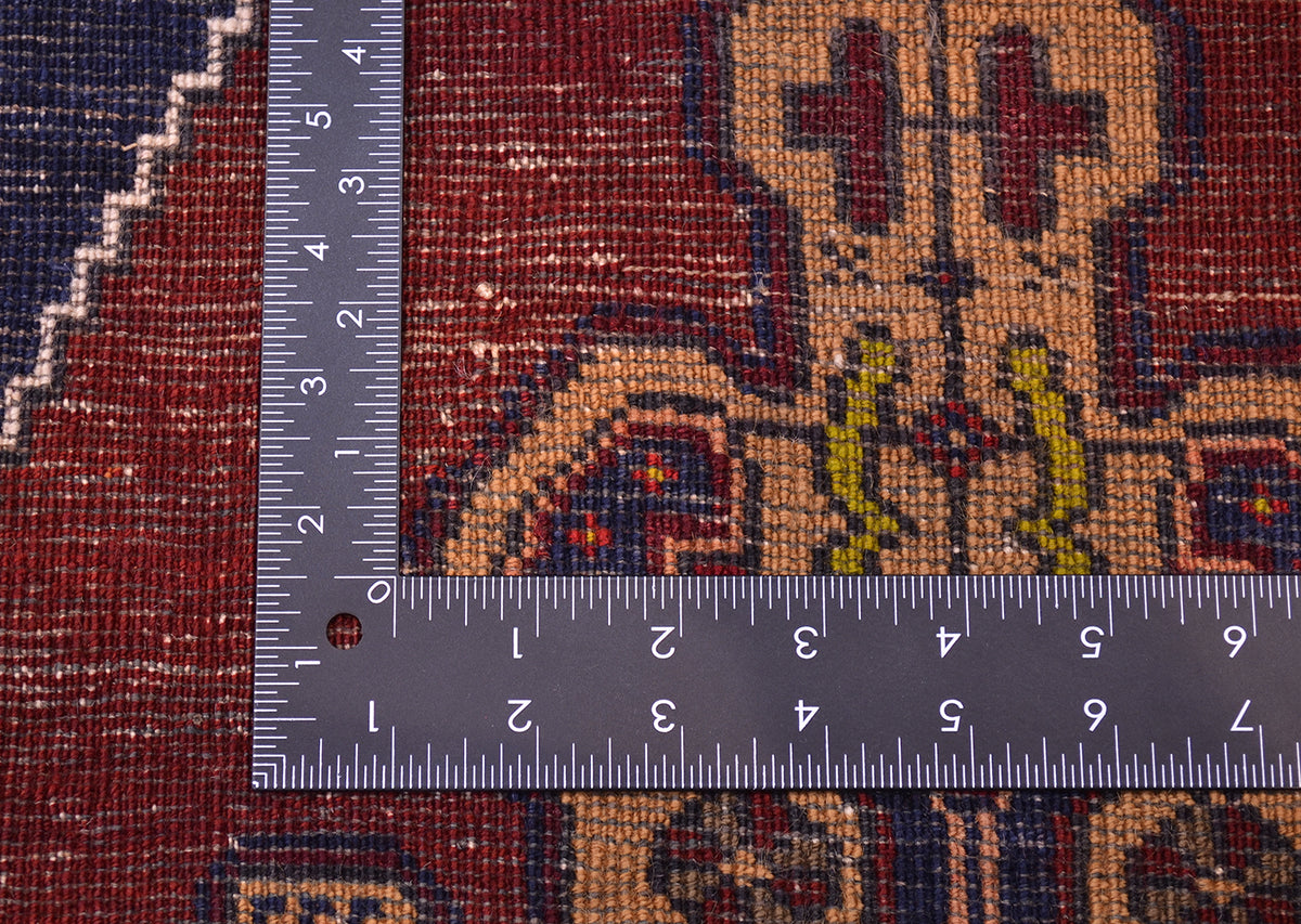 Close-up of the hand-knotted weave of a patterned Old Turkish Yahyali rug with a metal L-square ruler placed over it to show scale of the knotting.