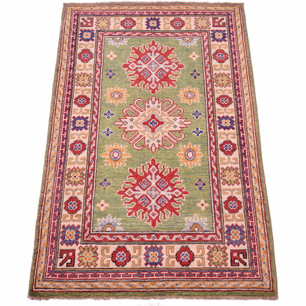 Handmade green wool rug, angled view, red and blue geometric medallions with border