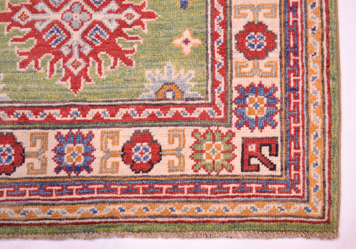 Green wool rug corner detail with red medallion and multicolor geometric border
