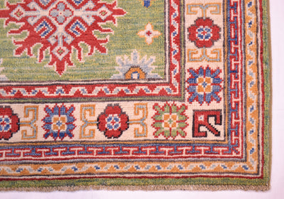 Green wool rug corner detail with red medallion and multicolor geometric border