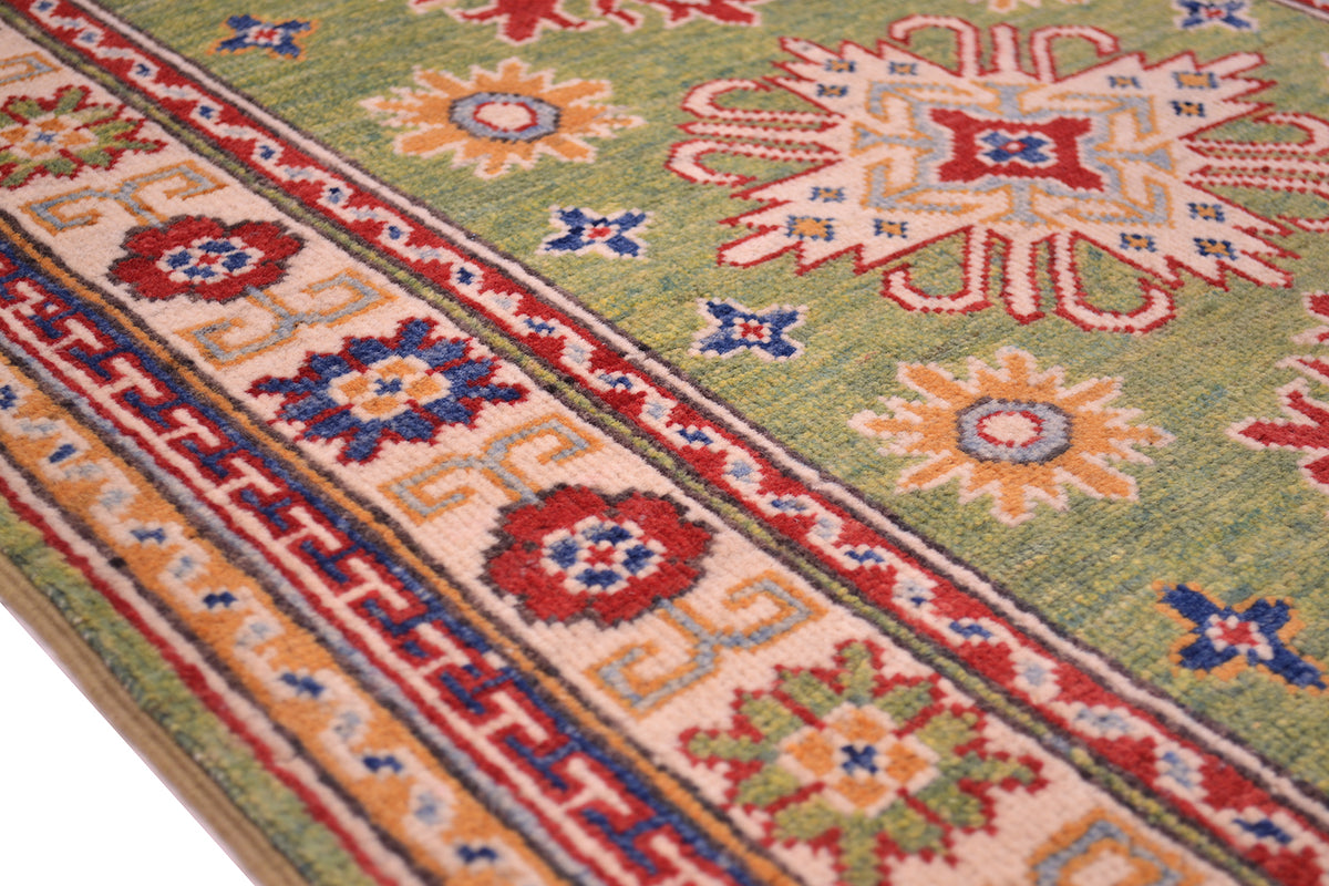 Green wool rug border close-up with red, blue, and orange diamond motif band