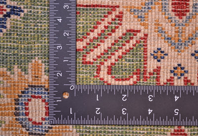 Green wool rug weave close-up with measuring tape over multicolor geometric design