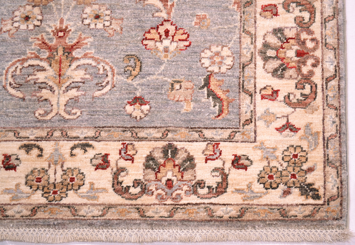 Corner detailing and floral border of afghan ziegler rug with latticed cotton warp fringe.