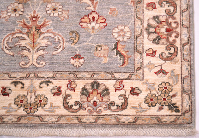 Corner detailing and floral border of afghan ziegler rug with latticed cotton warp fringe.