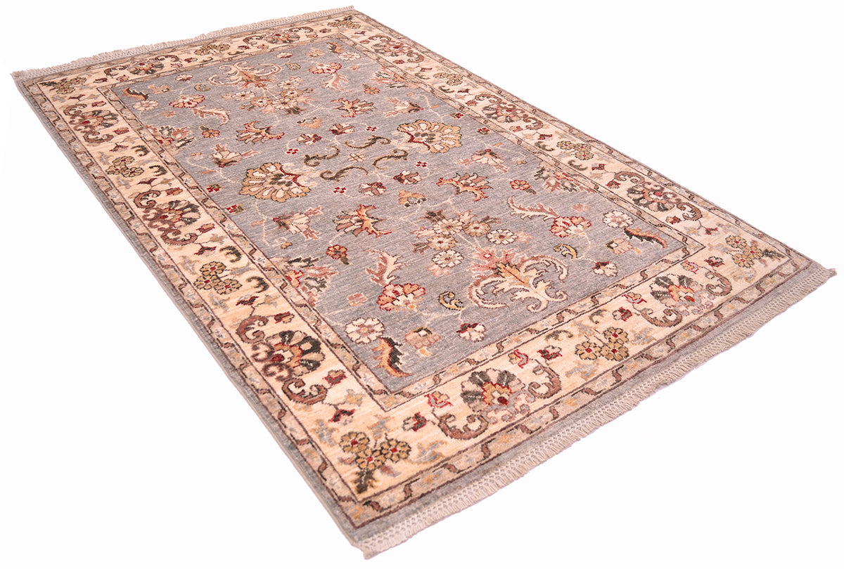 Angled view of handmade rug with cream/gold border and light grey field with floral rosette and lattice cotton warps