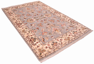 Angled view of handmade rug with cream/gold border and light grey field with floral rosette and lattice cotton warps