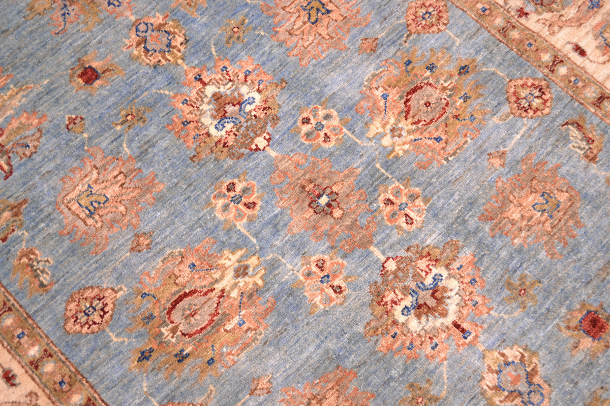 Handmade Afghan Ziegler rug close-up, light blue background with orange geometric motifs