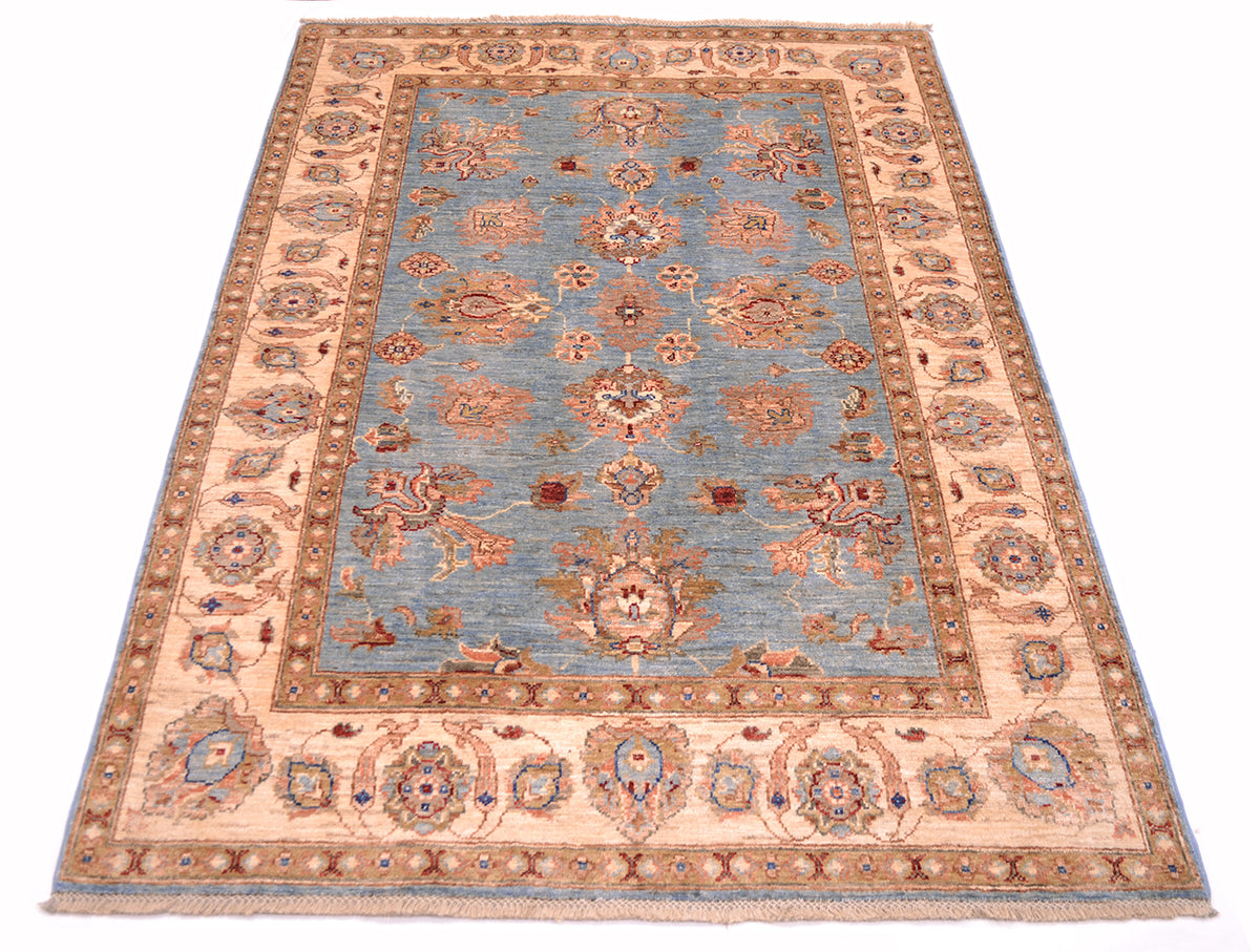 Handmade Afghan Ziegler rug angled view, light blue field with orange floral medallion