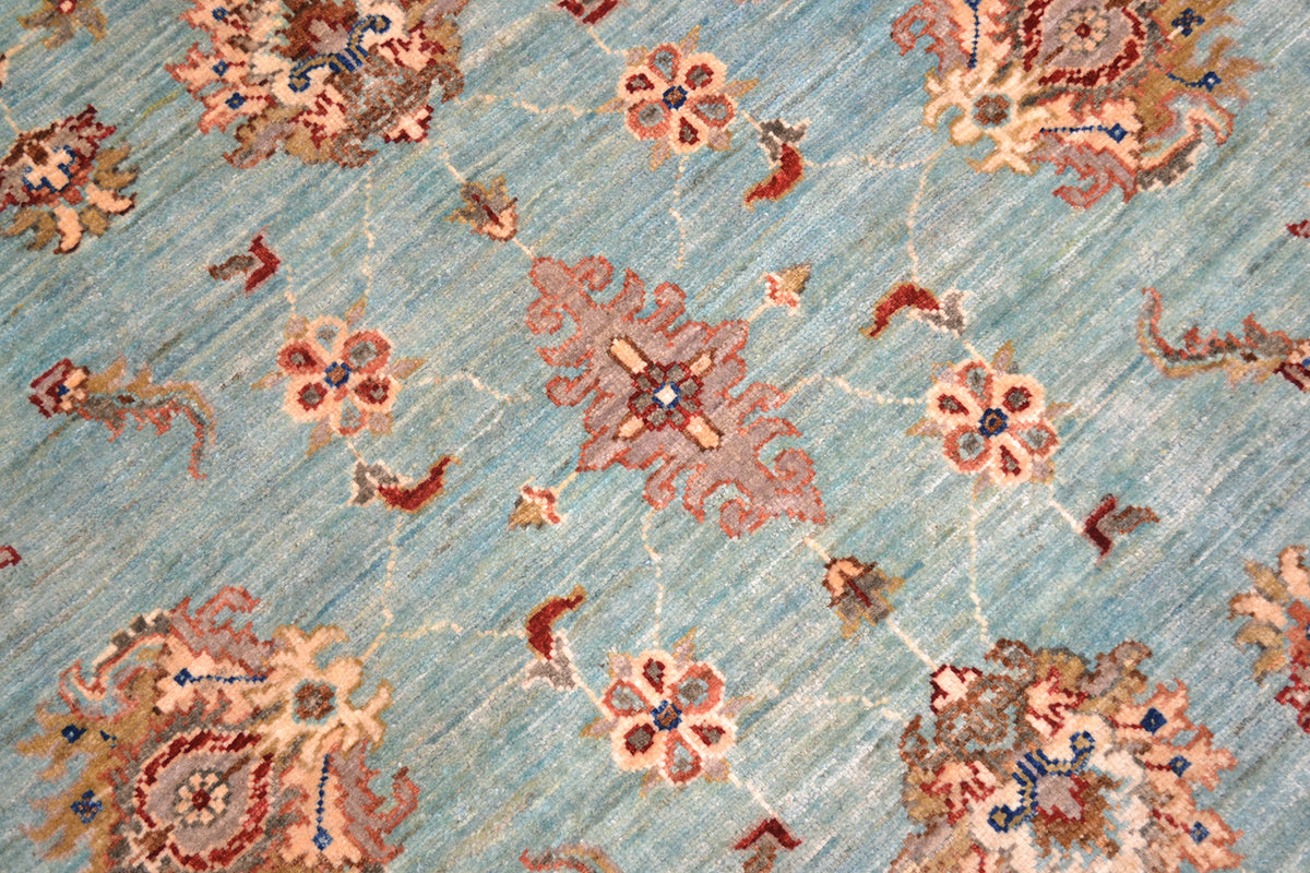 Close detail of handknotted pile of light blue aqua tones with soft coloured palmette and decorative flowers