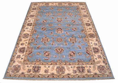Floating flowers in light blue field of handmade afghan carpet with cream and golden beige border.