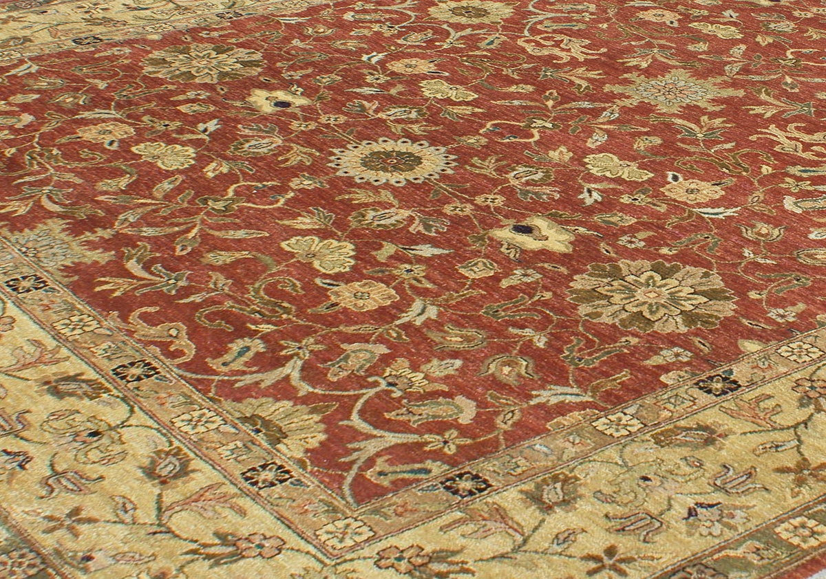 Detailed view of main field of amber rust toned field colour of oversize handknotted carpet with curvilinear  all-over floral motifs  within field and border. Roundels and rosettes and tendrils in main field.