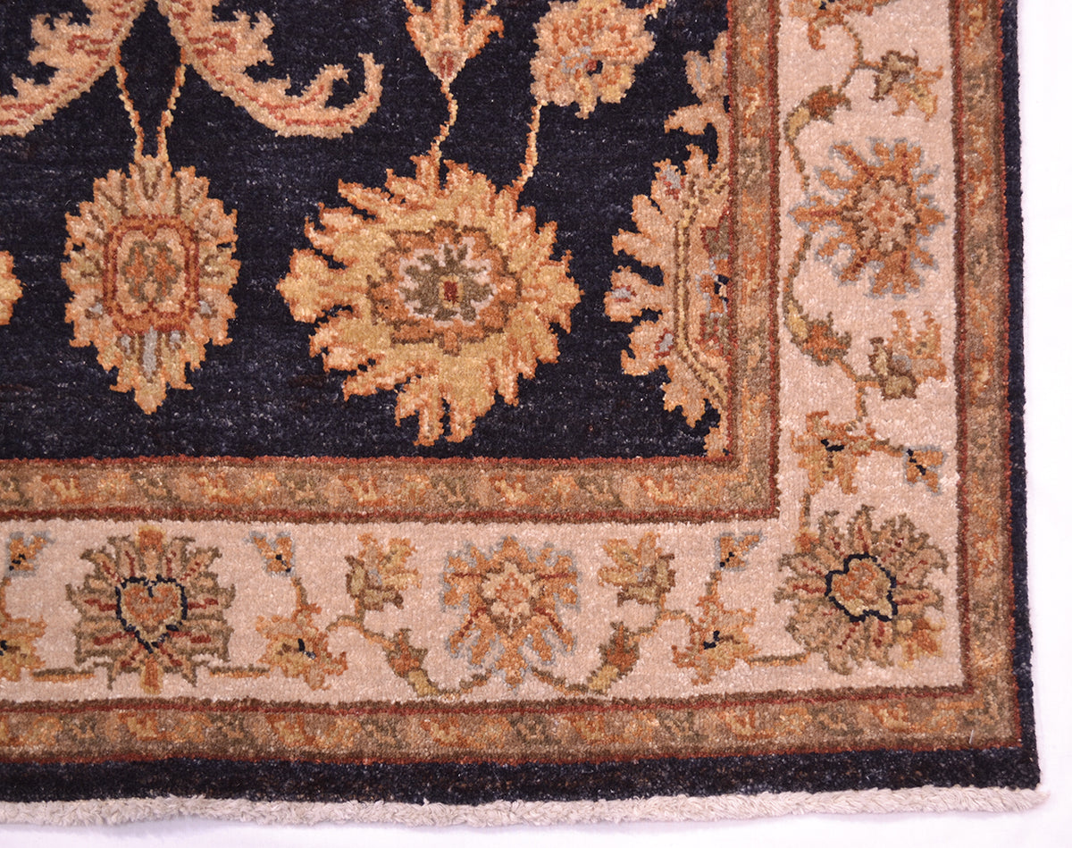 Rug corner detail with dark navy floral medallion and tan ornamental border
