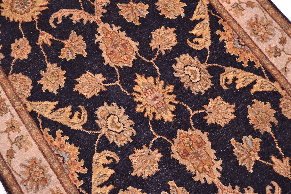 Floral rug detail with dark navy background and tan rust-gold blossoms and vines