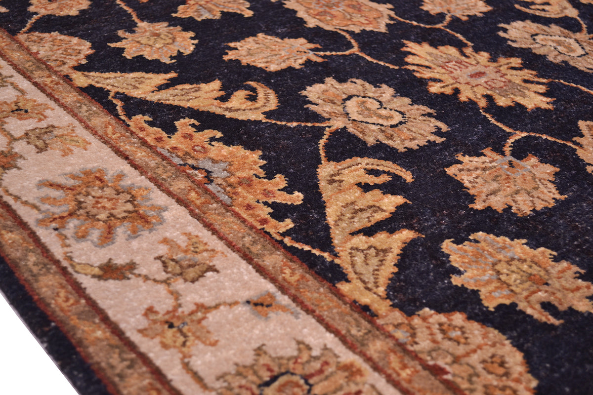 Rug border detail with tan panel and dark navy vine lines in rust-gold
