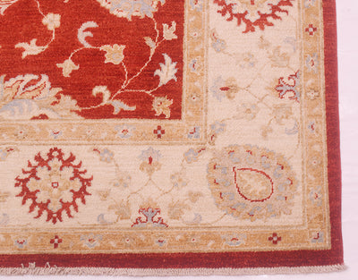 Corner detail and border of Afghan carpet in cream and rust red with cotton fringe warps