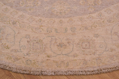 Detail of border of afghan ziegler circle rug with cream and beige background of border with floral motifs woven on cotton foundation.