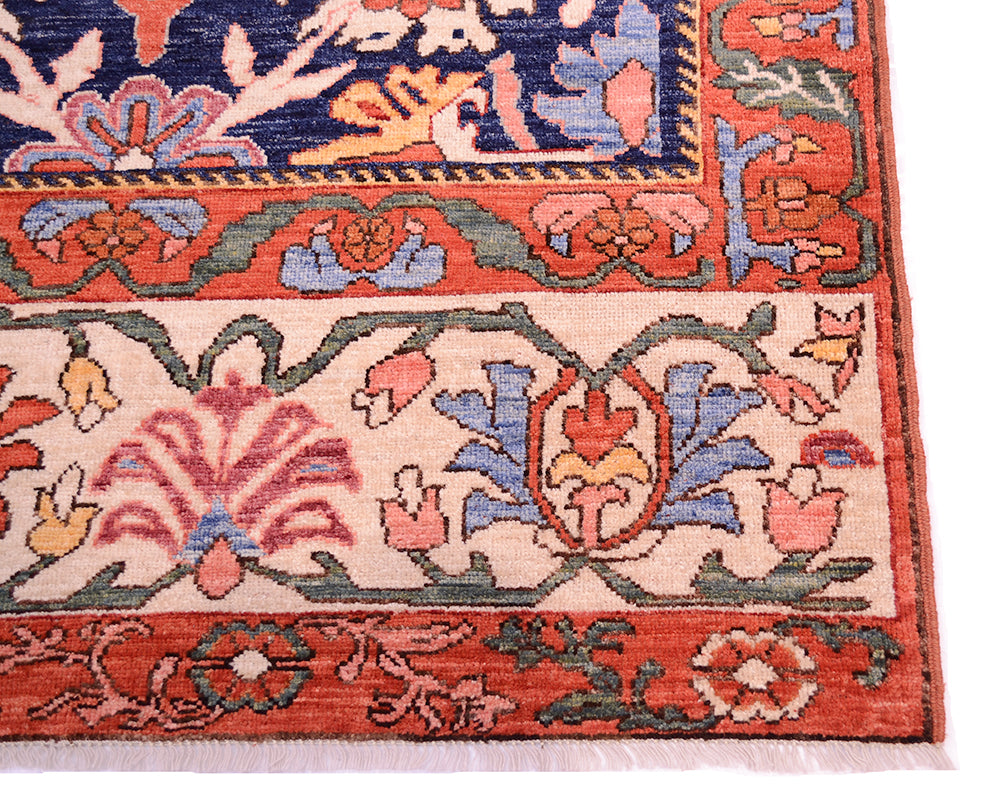 Antique floral rug corner detail with cream background, red-orange border, and blue floral motifs.