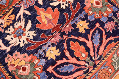 Close-up of antique floral rug texture with navy and orange floral motifs and multicolor details.