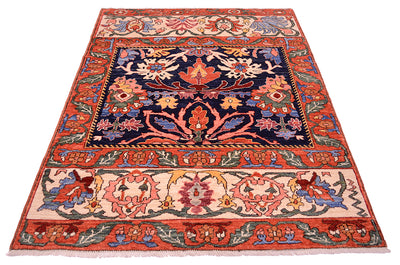Antique floral area rug with red-orange border, navy center, and cream floral band at bottom.