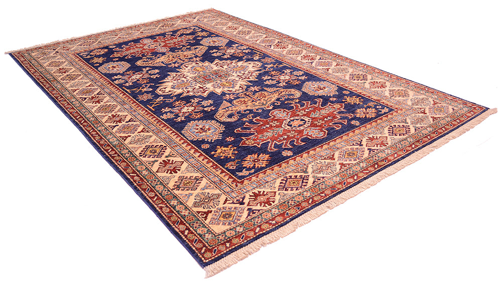 A traditional oriental Kazak area rug with a navy blue central field, intricate floral motifs, and a wide beige and red patterned border, shown on a plain white background.