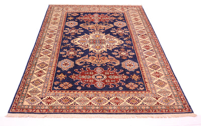 A traditional oriental fine Kazak area rug with a navy blue centre, beige and red borders, and cream fringe, shown flat against a white background.