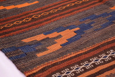 Close-up Qala-i-Nau kilim rug texture with orange, blue, and brown geometric bands